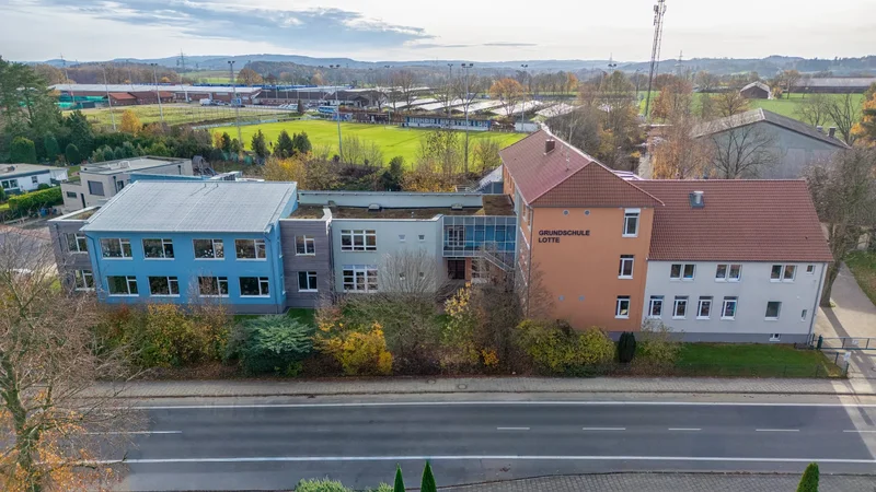 Luftaufnahme des Schulgebäudes der Grundschule Lotte mit dem Schriftzug „Grundschule Lotte" am Giebel