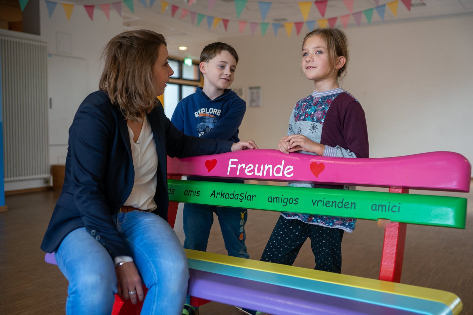 Kinder sitzen auf der Freundschaftsbank auf dem Schulhof der Grundschule Lotte.