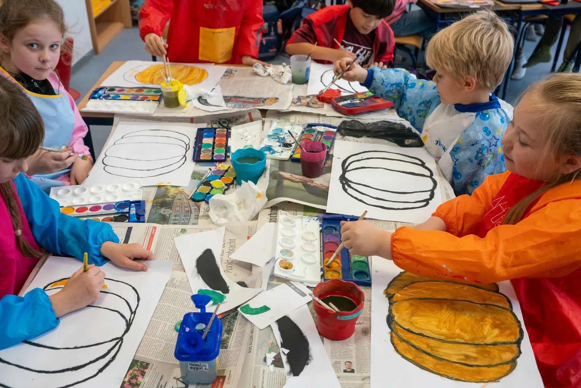 Kinder malen Kürbisbilder im Kunstunterricht.