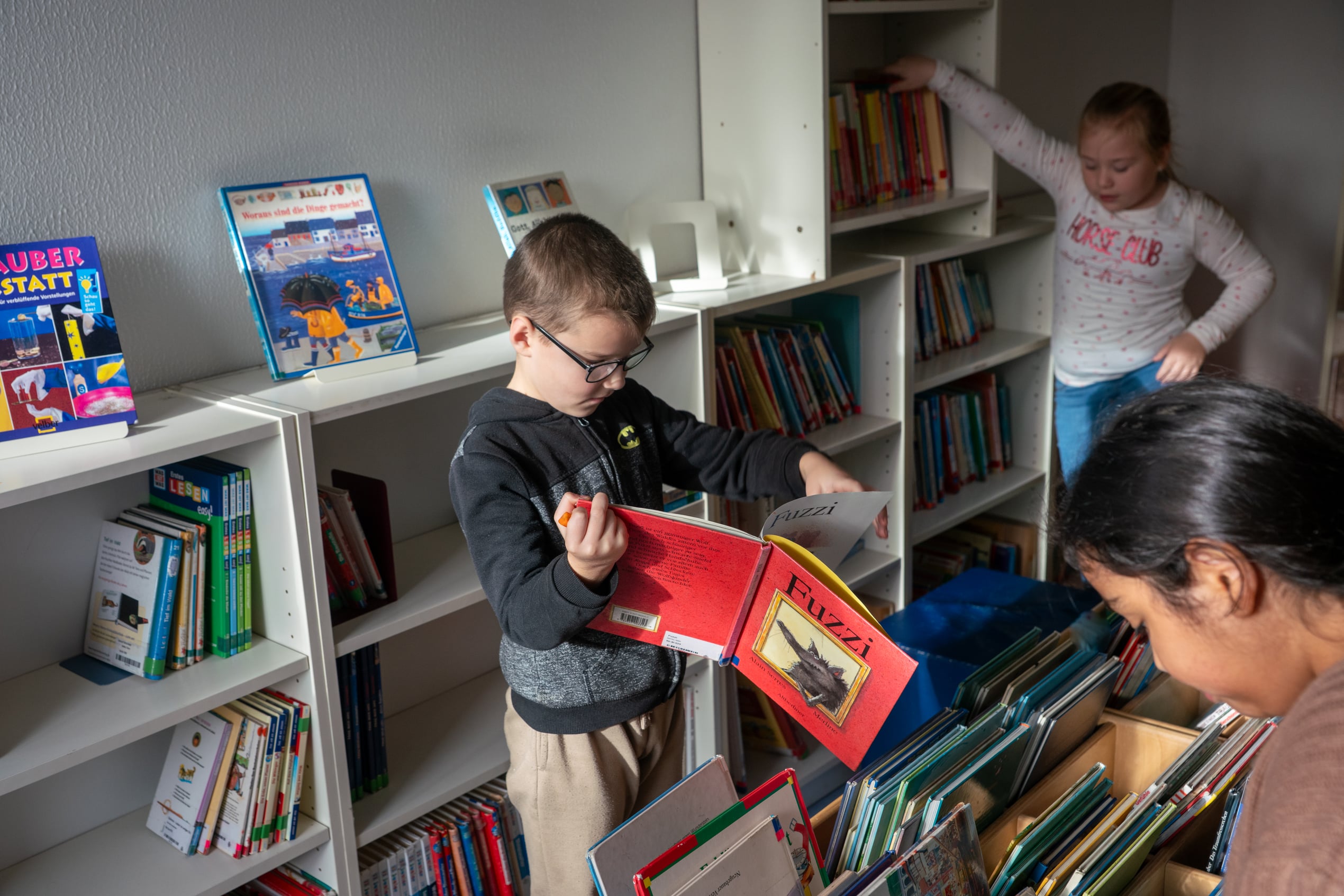 Schülerinnen und Schüler lesen Bücher in der Schulbücherei.